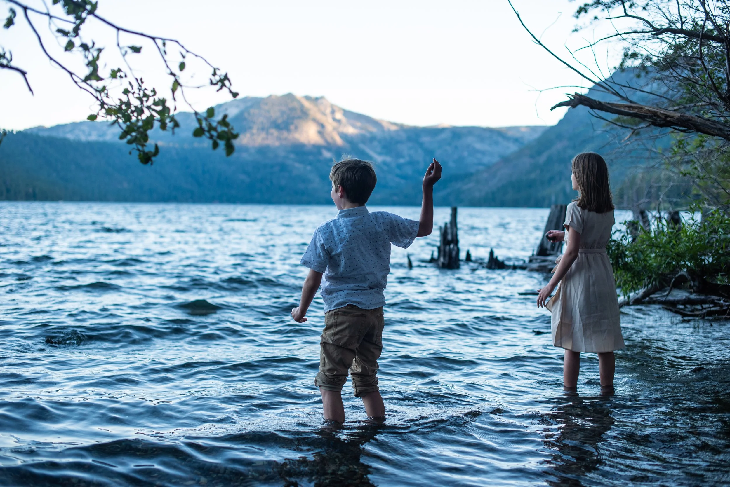 Kids wading in the water skipping rocks