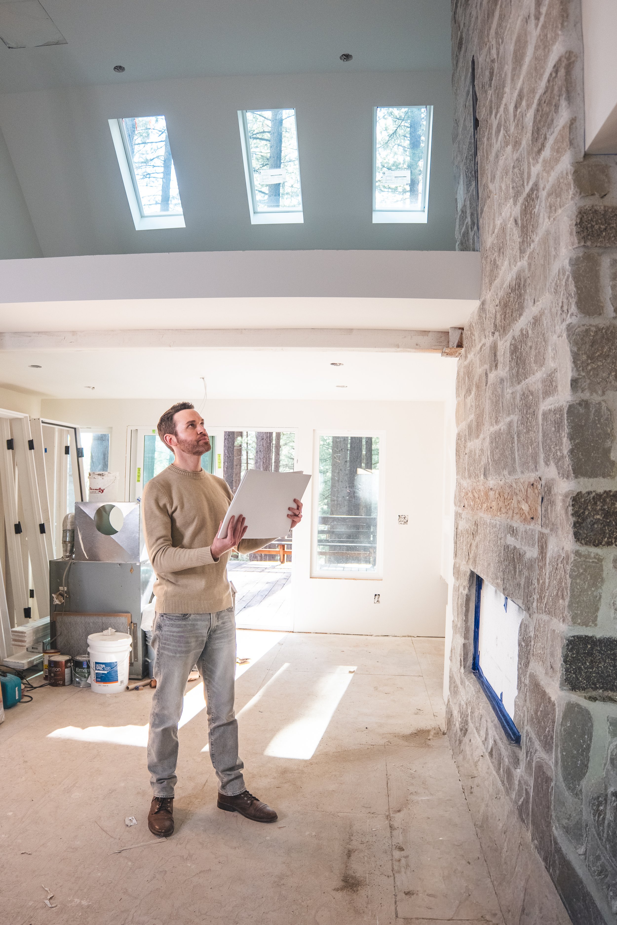 Personal branding photo of an interior designer looking at a fireplace while holding plans