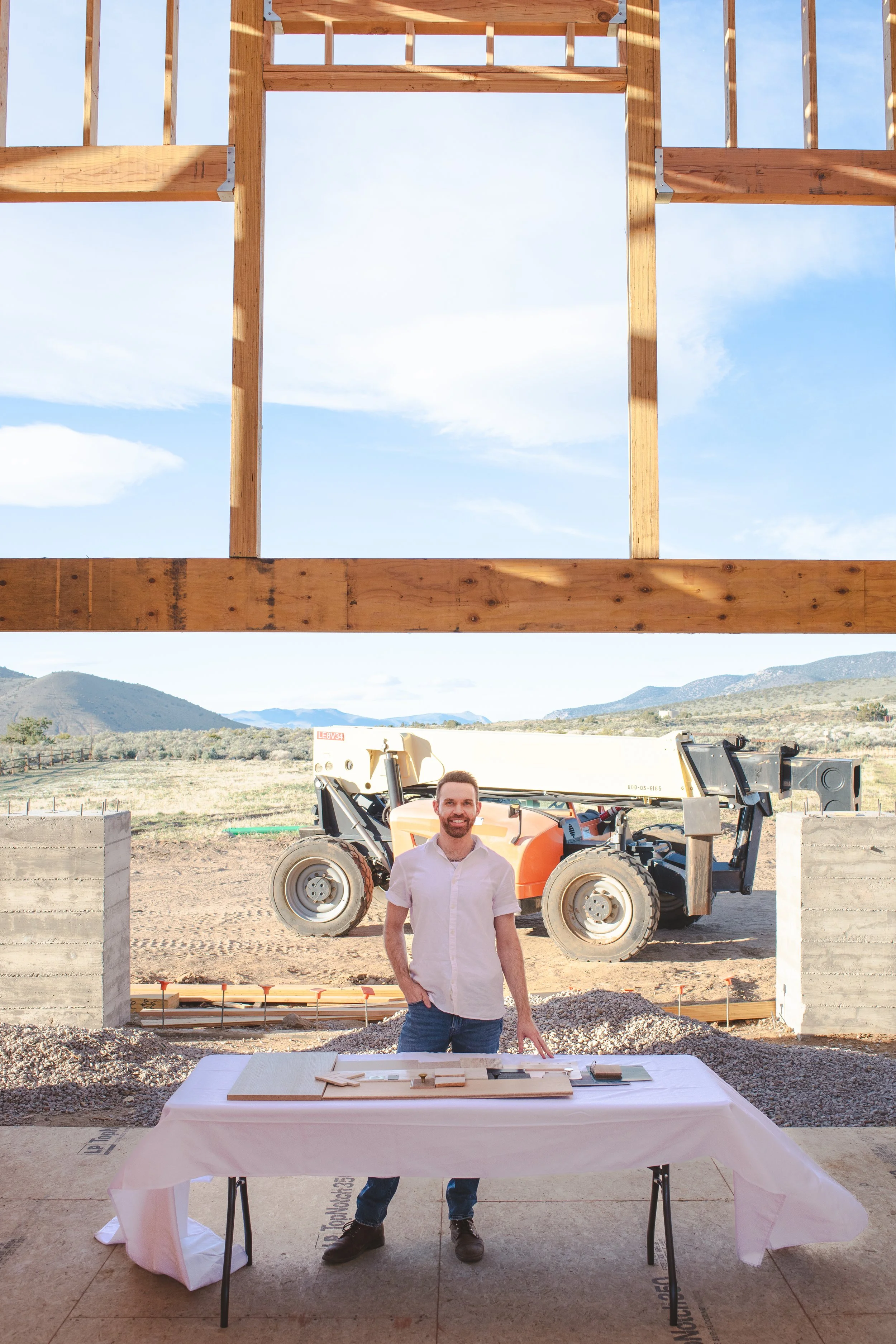 Personal branding photo of interior designer standing in a framed house with a table of materials samples