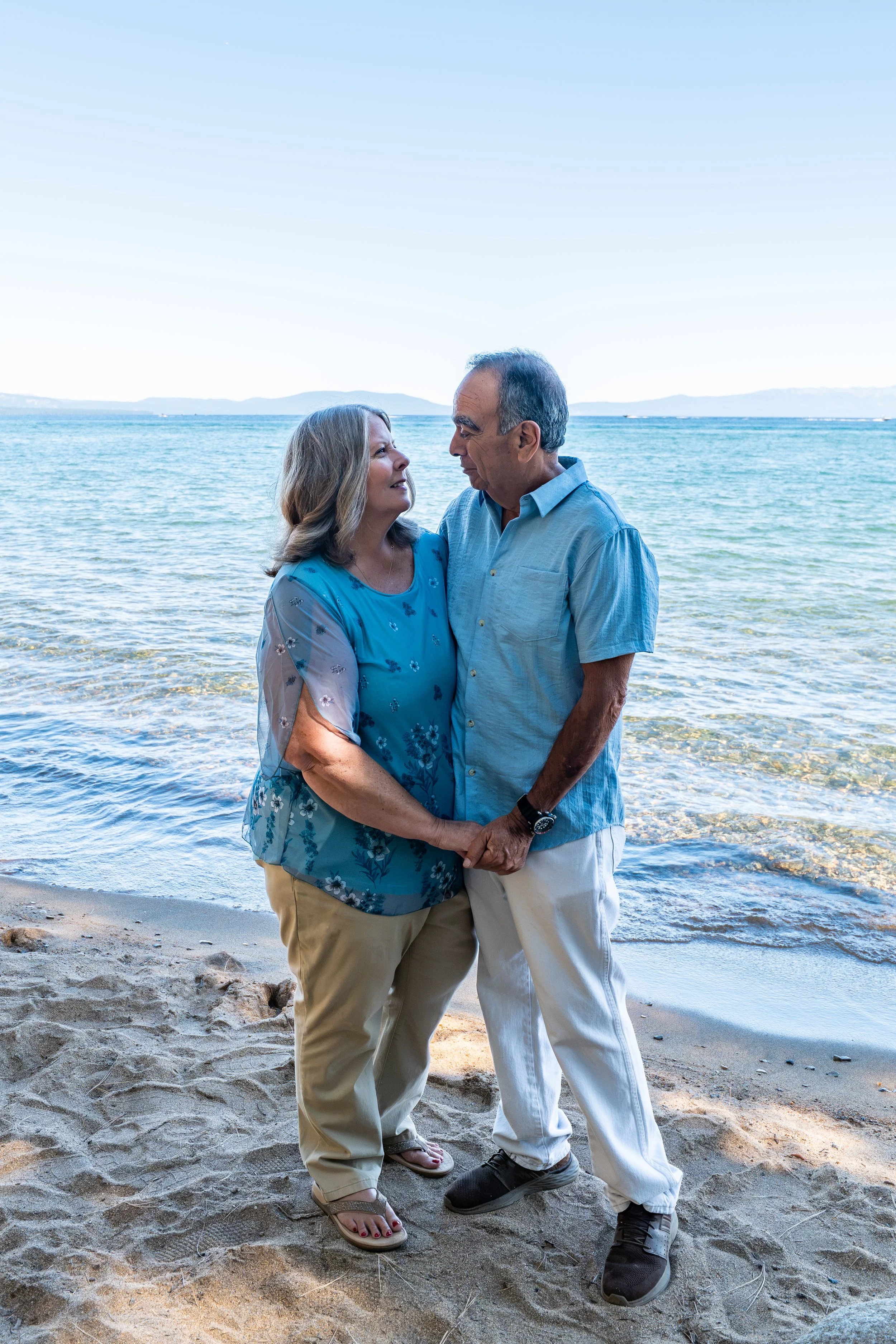 Couple holing hands and looking at each other on the beach at Lake Tahoe