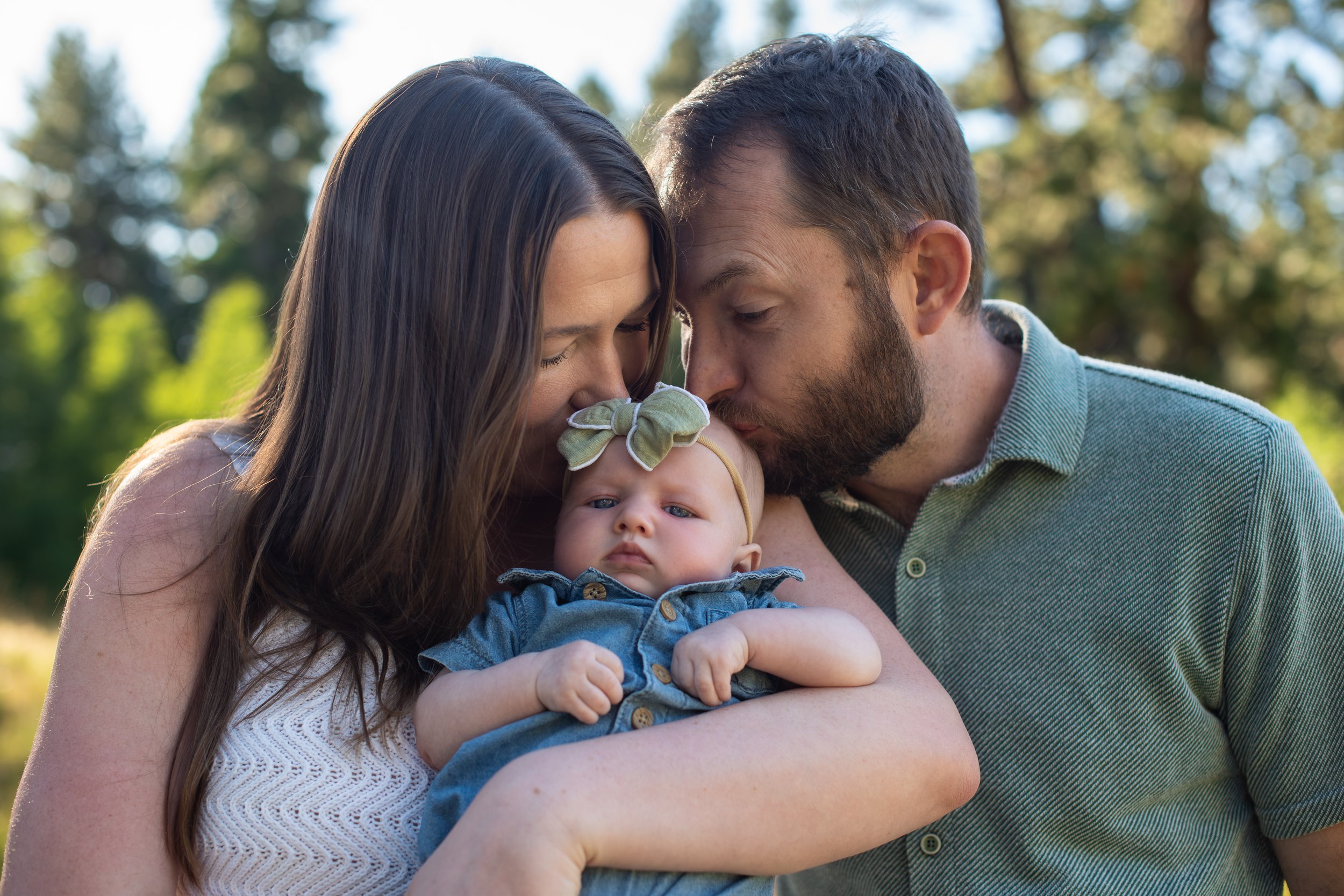 Mom and dad kissing the top of baby's head