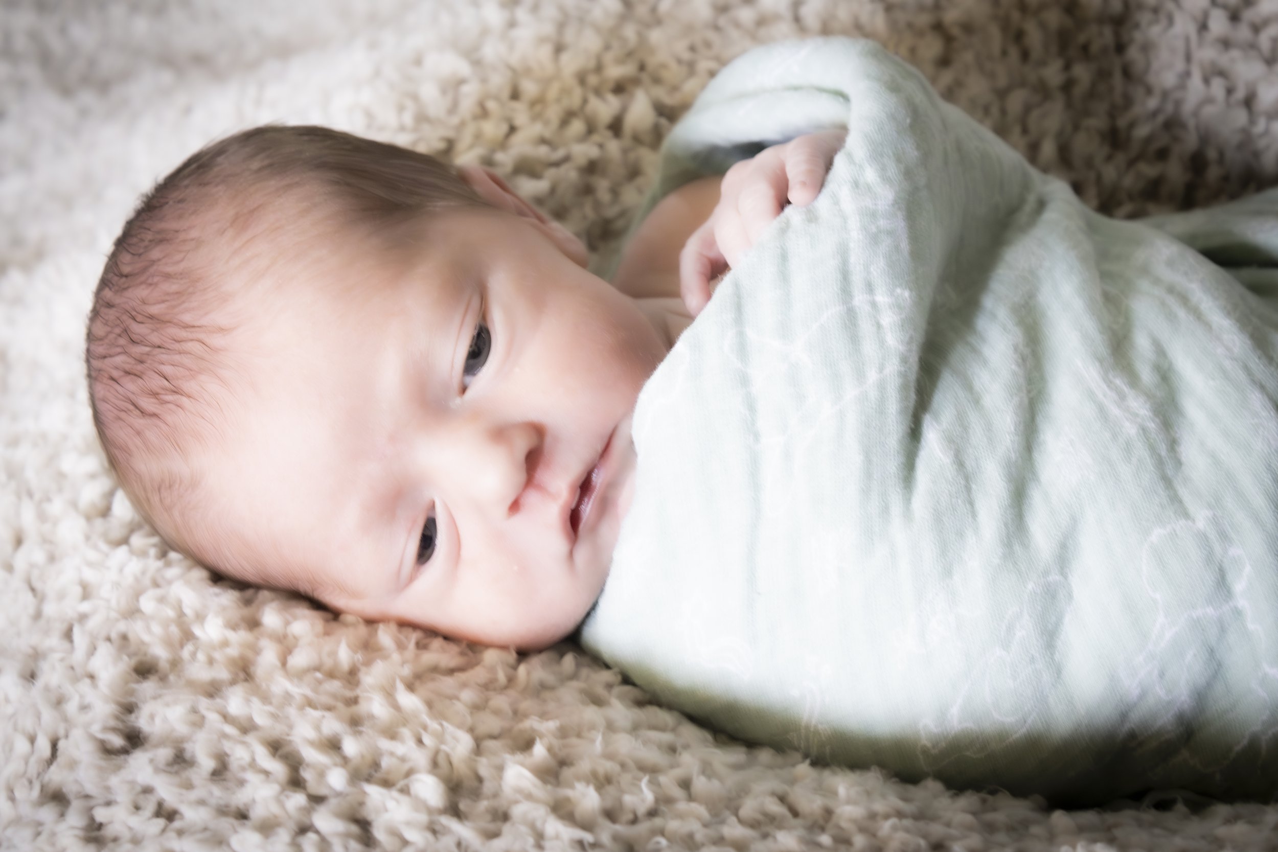 Newborn baby swaddled in a green cloth