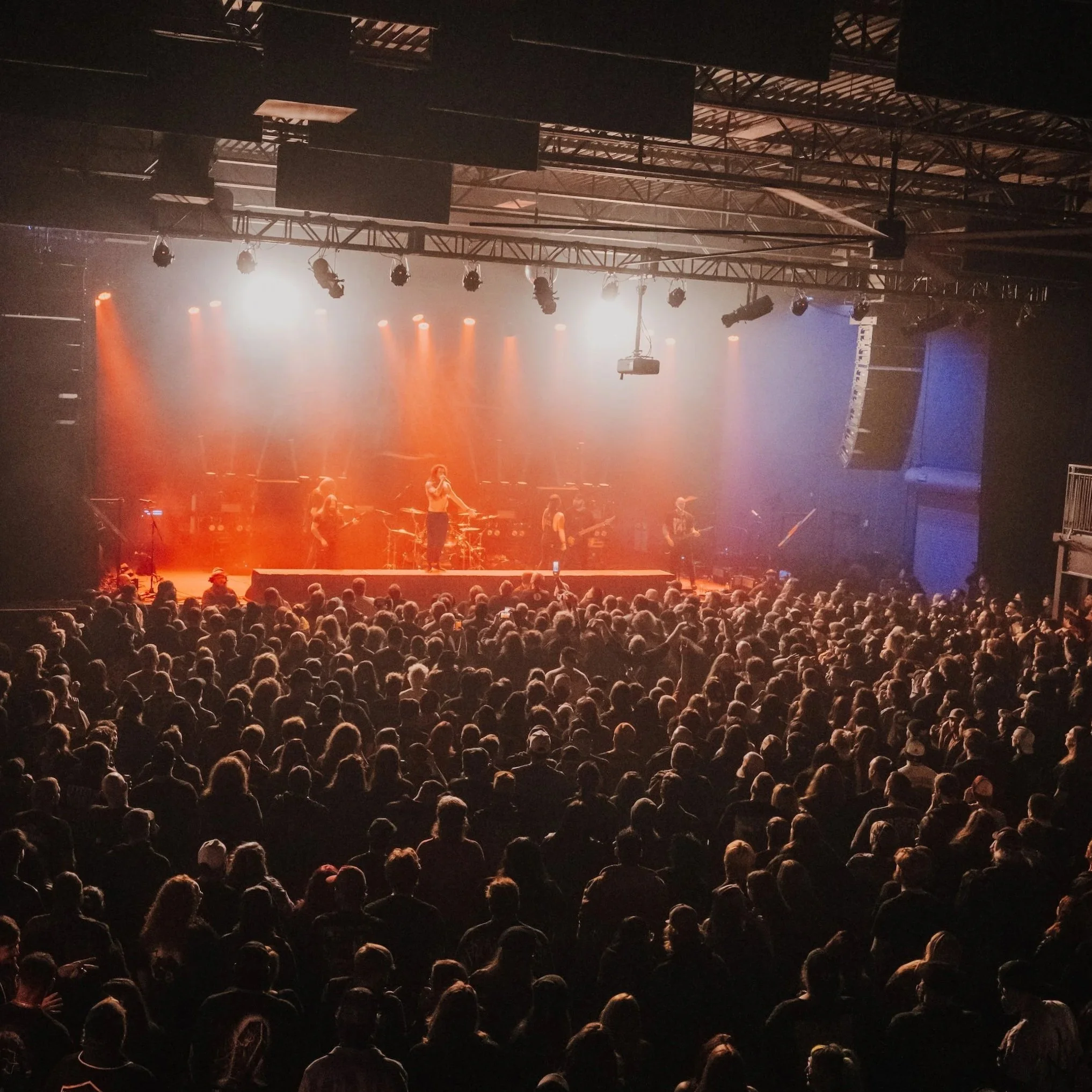 Crowd watching a concert on stage with band playing live at night.