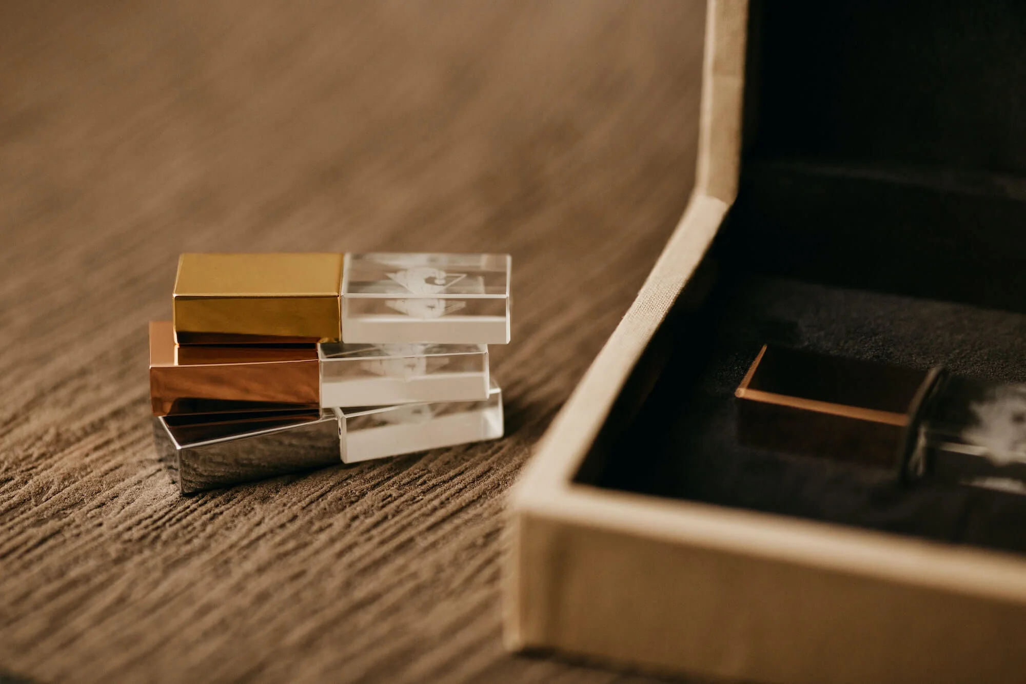 Stack of small rectangular mirrors with gold, silver, and clear designs, placed on a textured brown surface near a beige book or box.