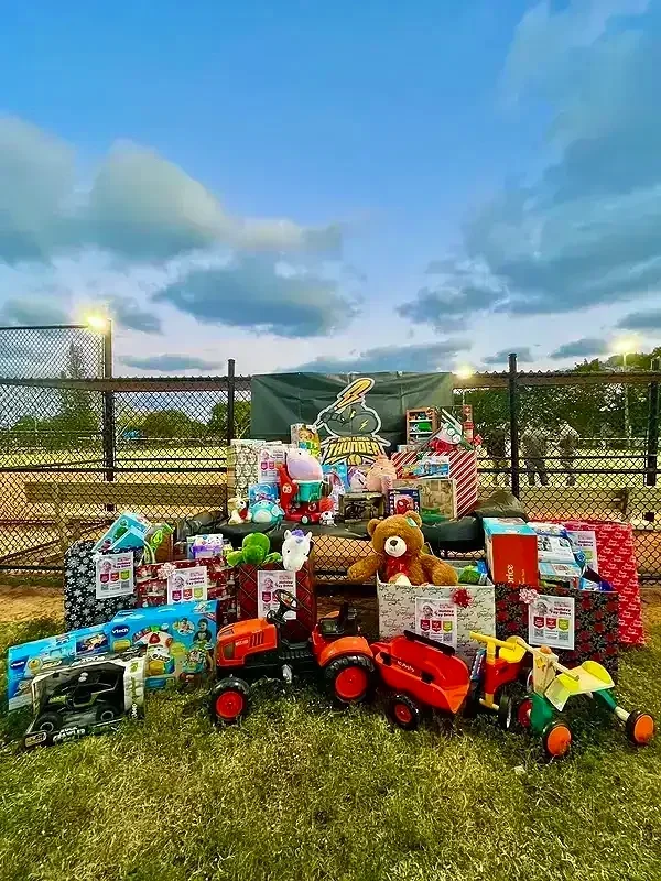 Christmas toy donation stand with toys and plush animals at a sports field during the day.