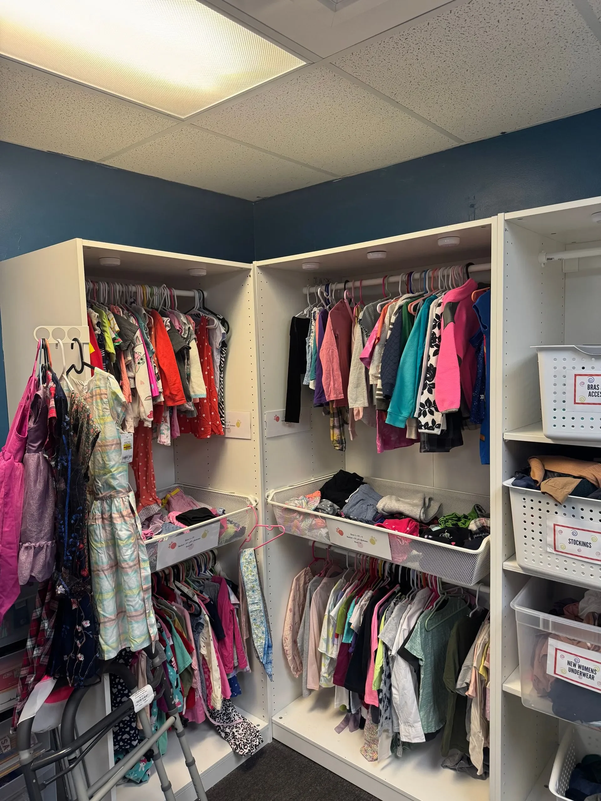 Closet with children's clothing on white shelves and racks