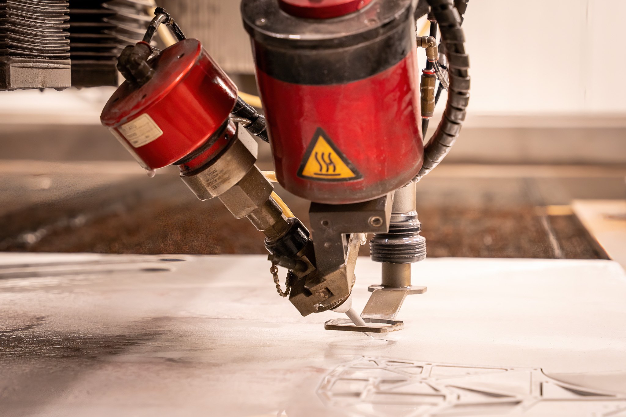 A CNC machine router working on a large sheet of material, carving out a design or pattern.