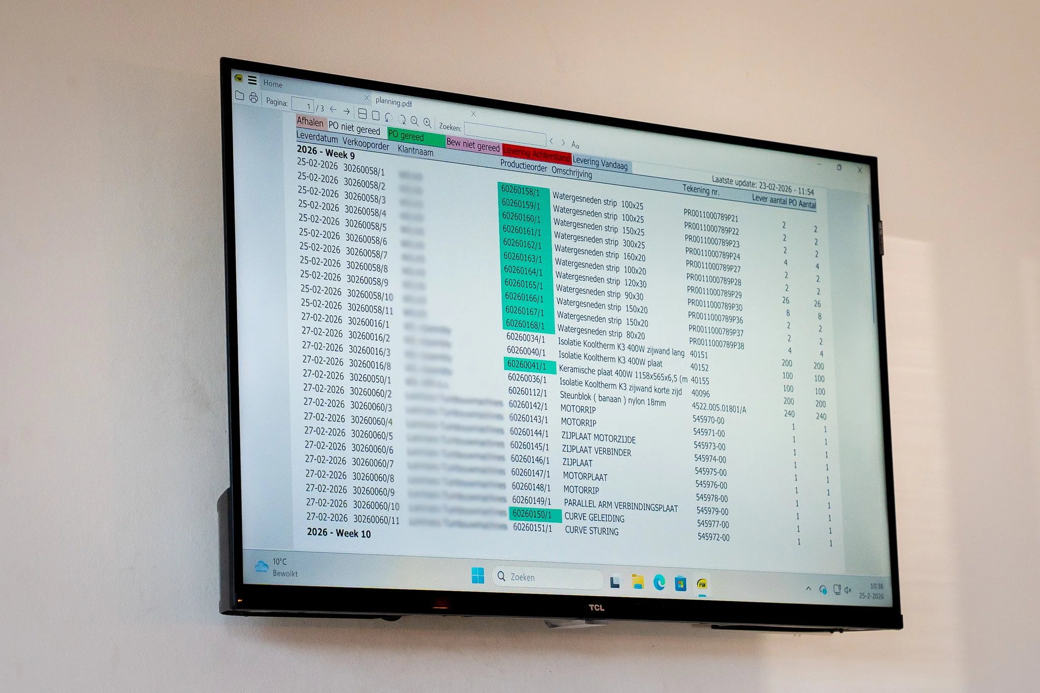 Computer monitor displaying a detailed spreadsheet with columns and rows of data, including dates, item descriptions, and quantities, on a white wall background.