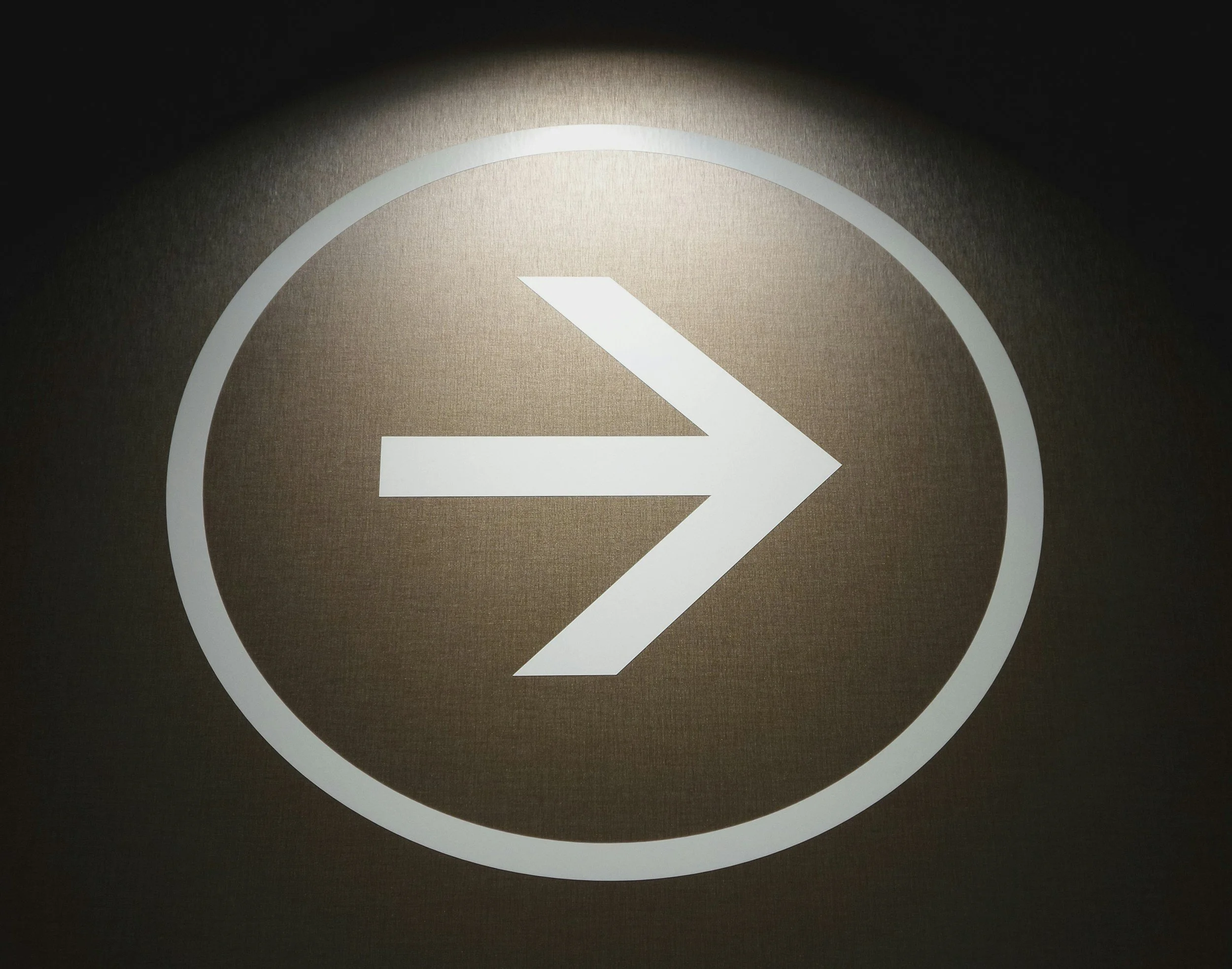 Illuminated sign with a right-pointing arrow inside a circle.