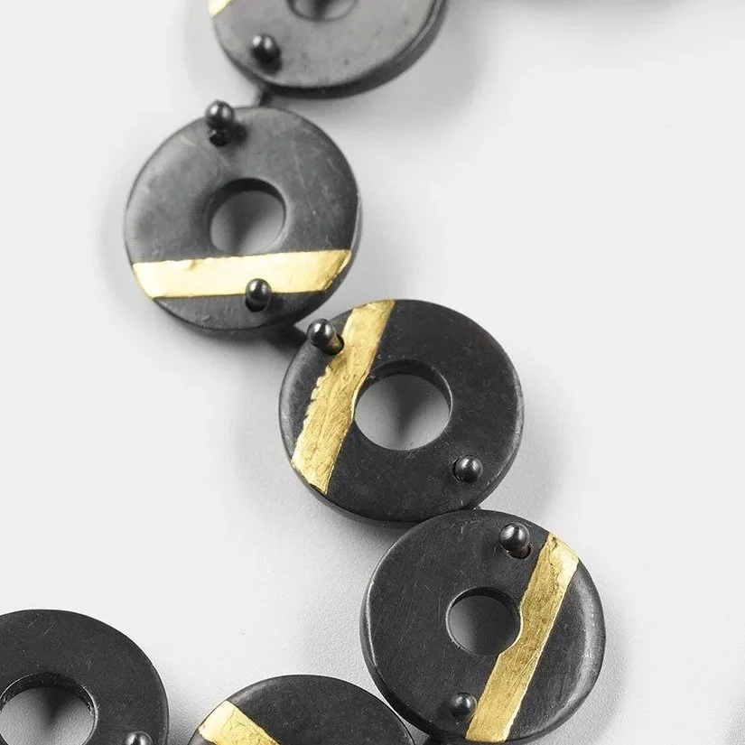 Close-up of Chronos bracelet showing oxidised torus forms and gold stripe detail