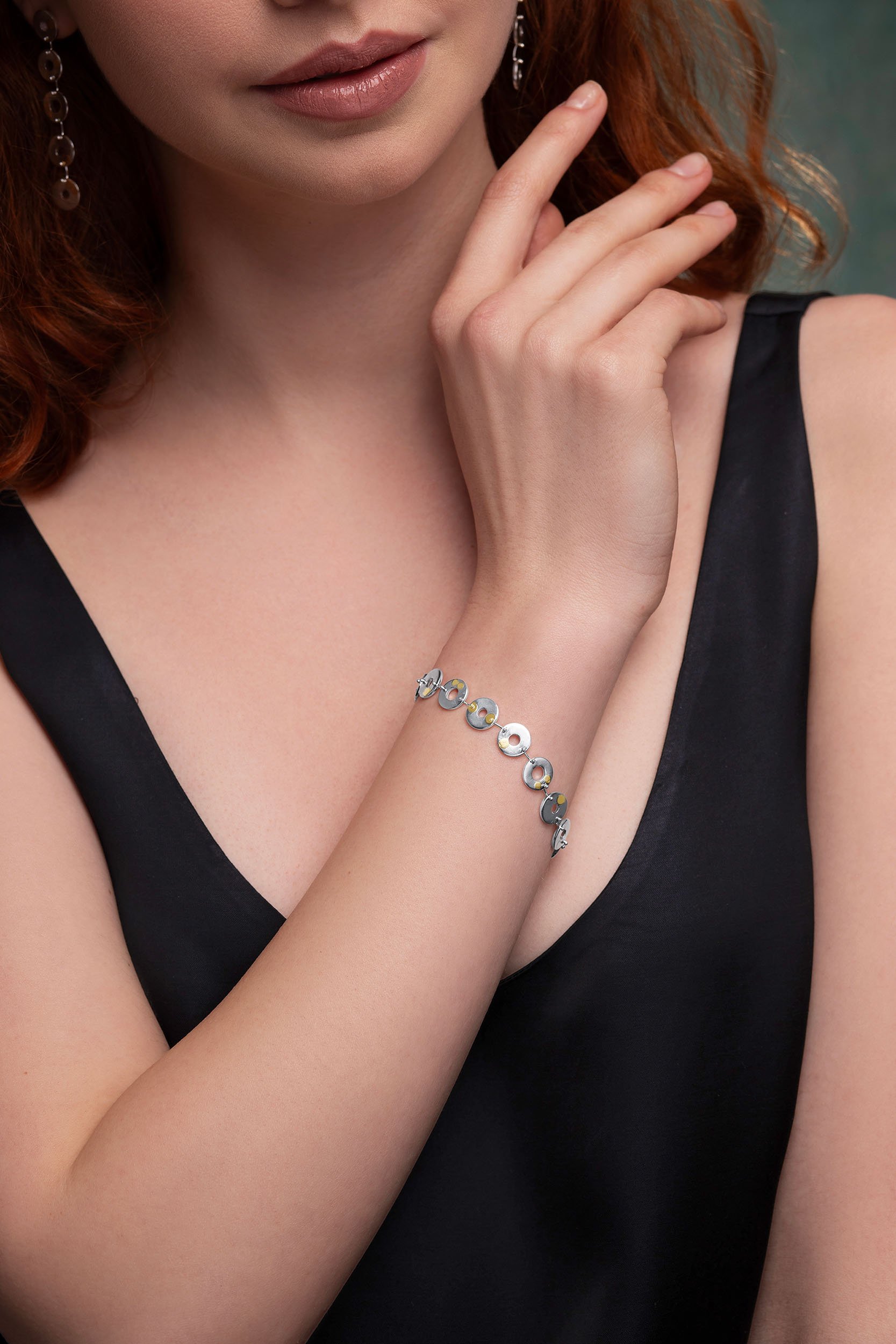 Close-up of model wearing sterling silver Kairoi bracelet with linked torus discs and 24ct gold keum boo detailing.
