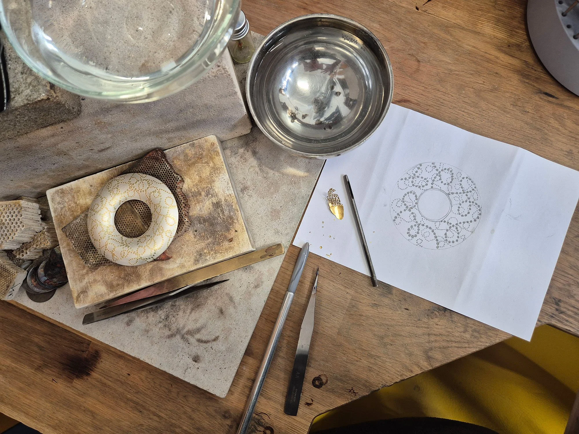 Jewellery bench with sketch and keum boo tools during the making process of a sterling silver piece