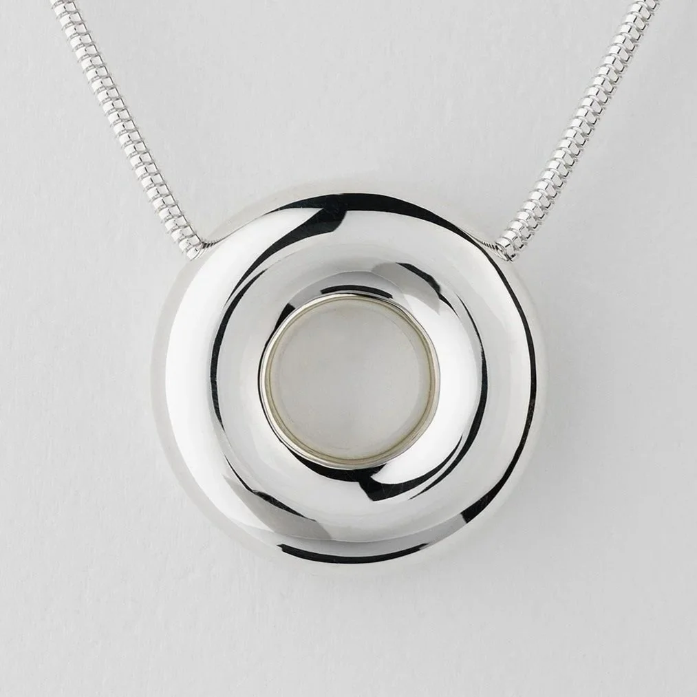 Close-up of Monad statement necklace showing polished circular torus pendant in sterling silver