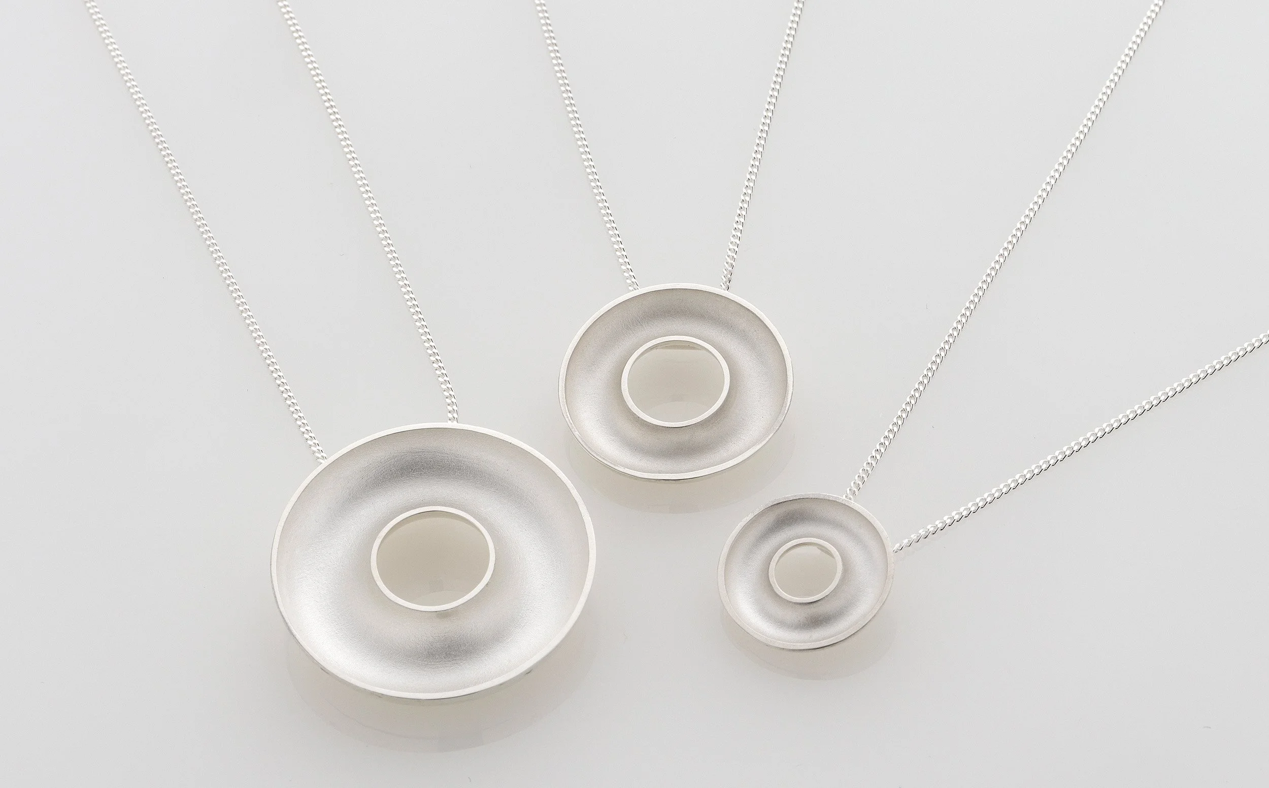 Sterling silver Orbis necklaces in large, medium and small sizes, concave torus pendants shown together