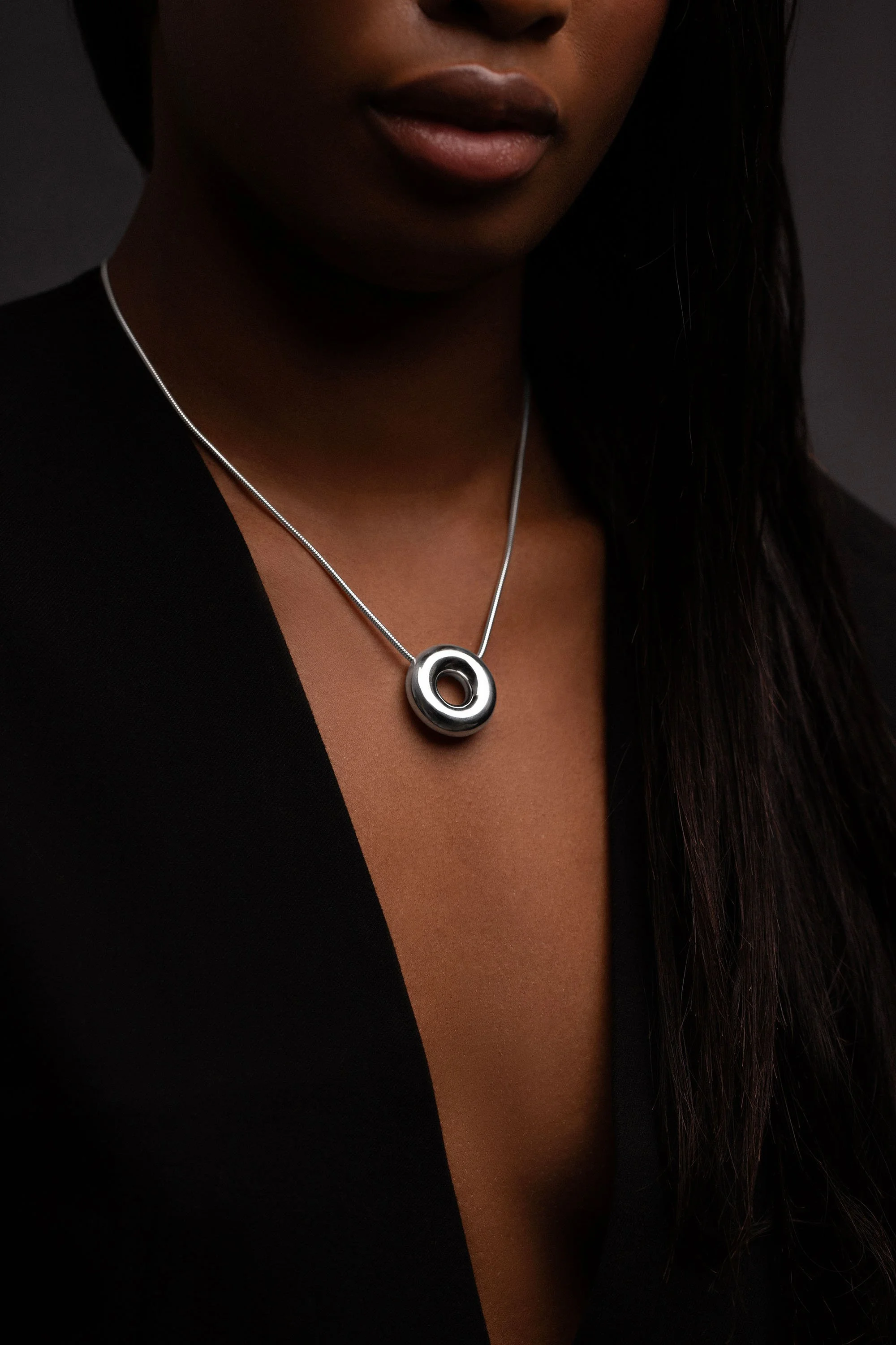 Model wearing sterling silver Monad necklace with polished torus pendant on chain
