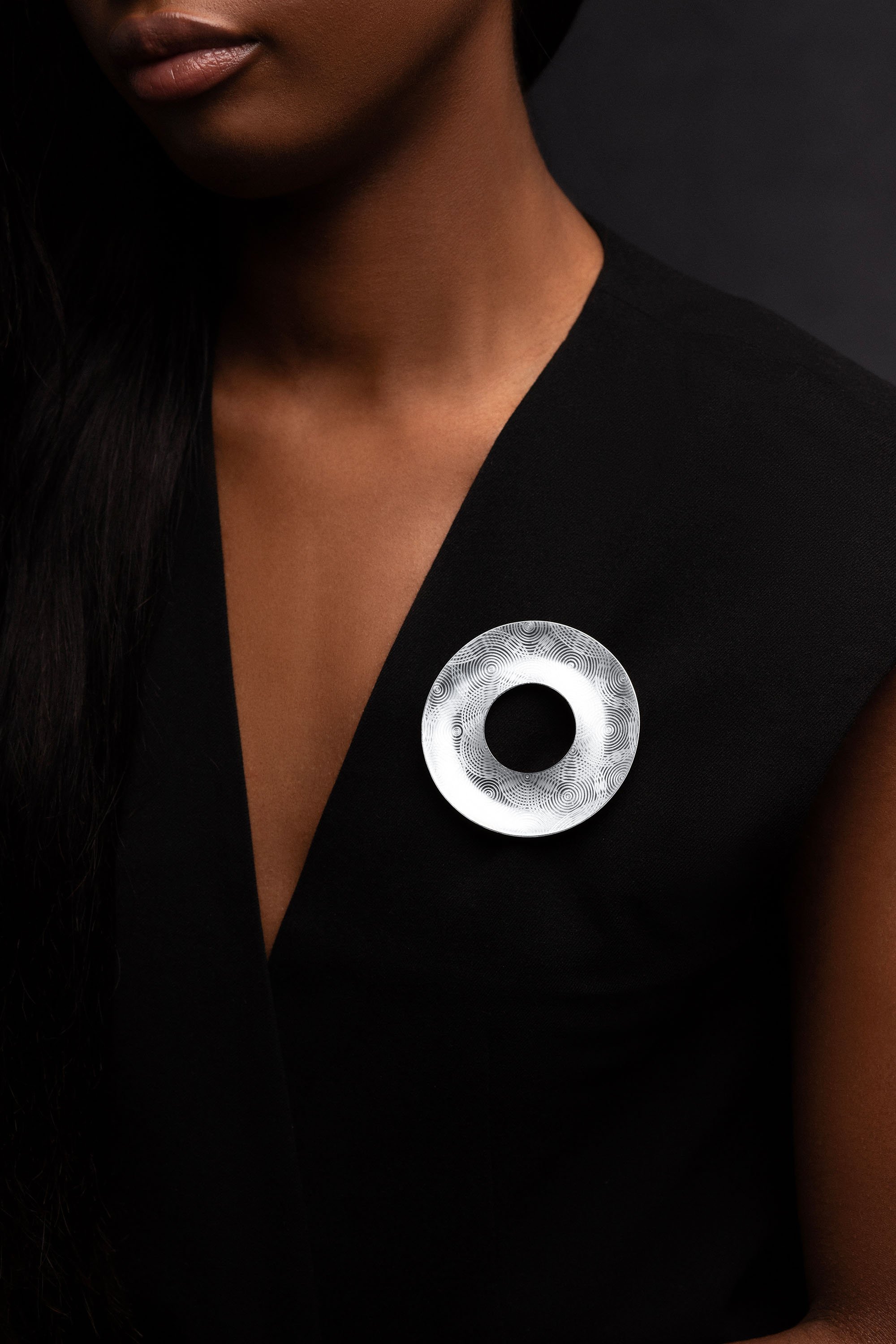 Model wearing sterling silver Ripples brooch, circular engraved surface design