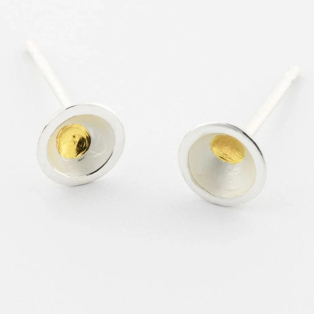 Close-up of domed white silver stud earrings showing central gold keum boo dot and polished edge detail