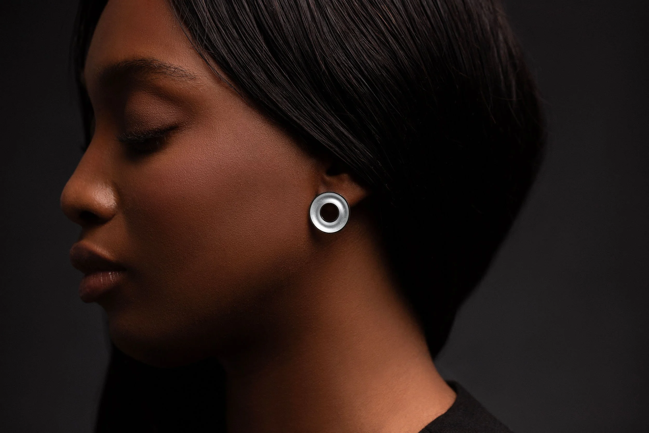 Close-up of model wearing Orbis medium stud earrings, concave torus form