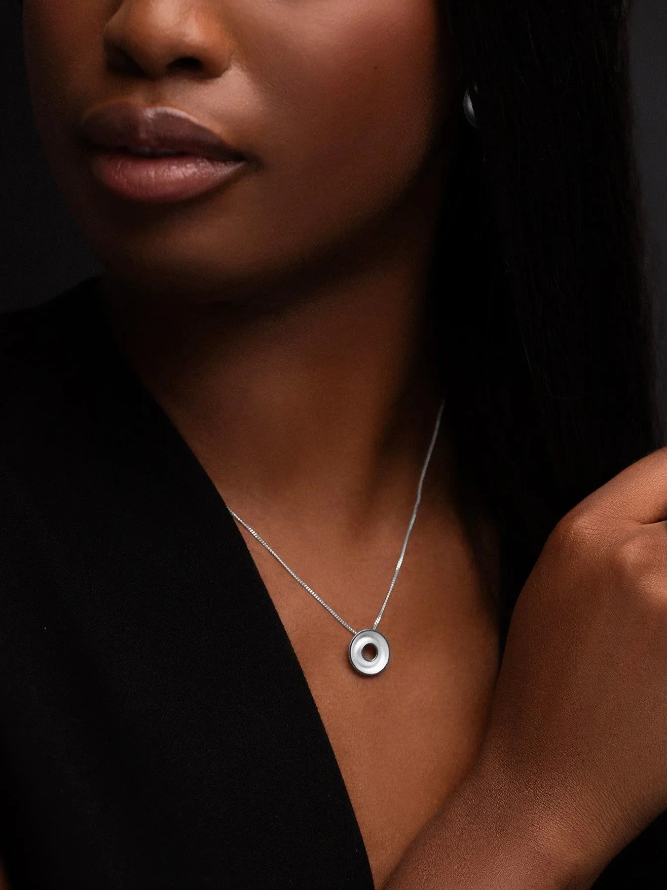 Model wearing small sterling silver Orbis necklace with polished torus form