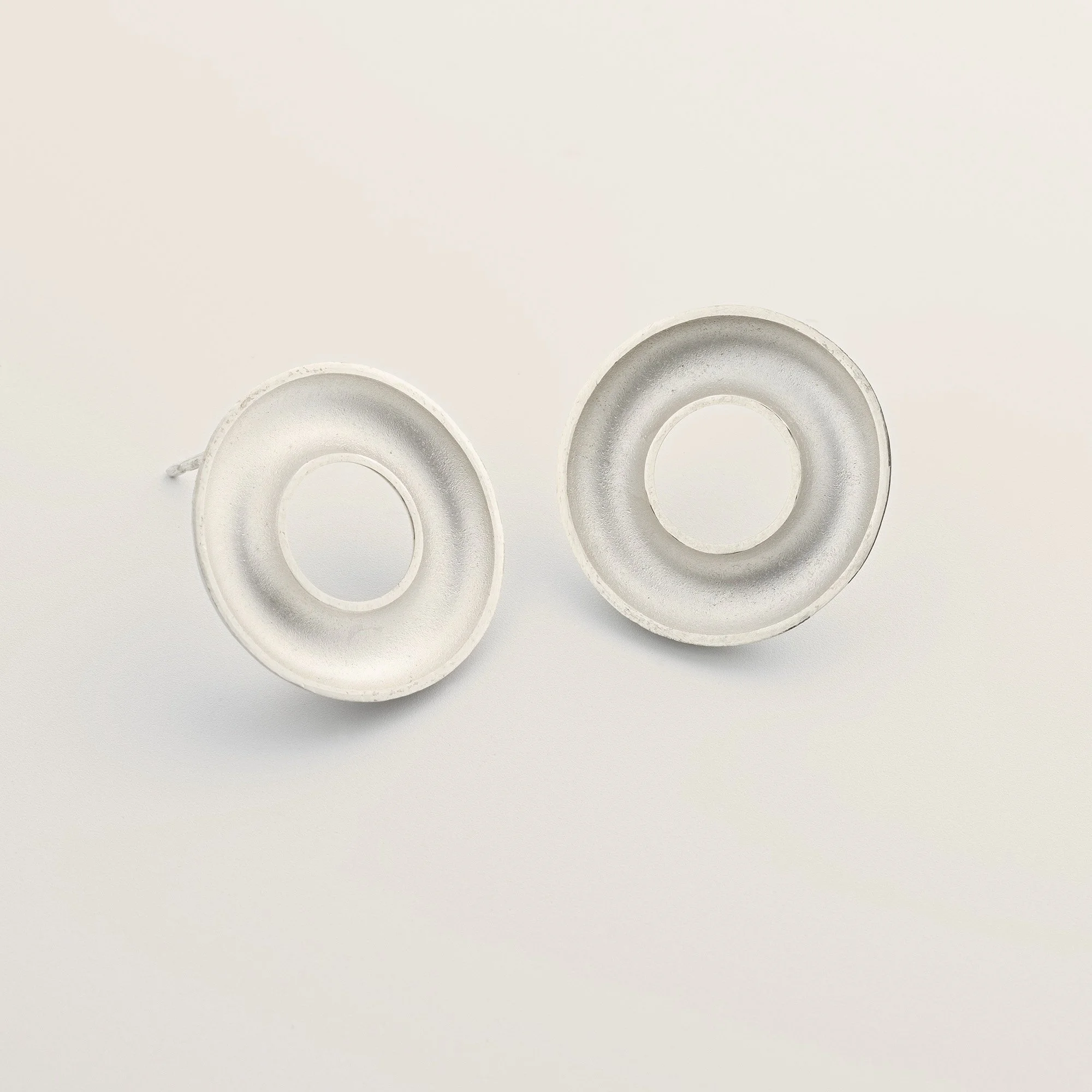 Sterling silver Orbis medium stud earrings with concave torus form and white interior