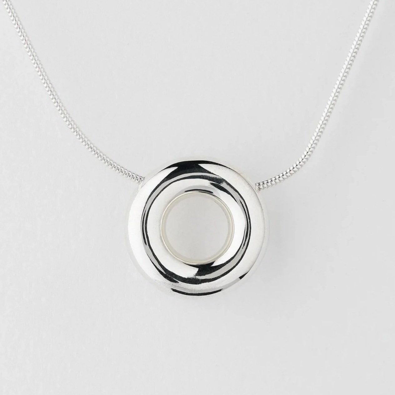 Close-up of Monad medium necklace showing polished circular torus pendant in sterling silver
