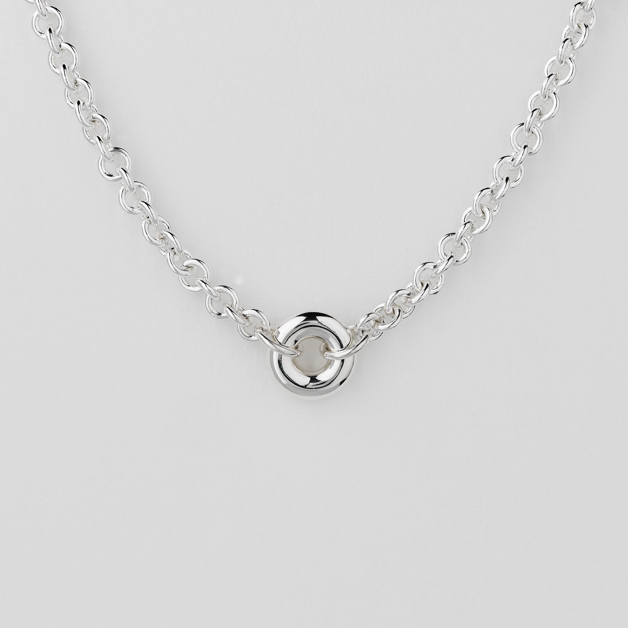 Close-up of Monad chain necklace showing hollow torus link and T-bar clasp in sterling silver