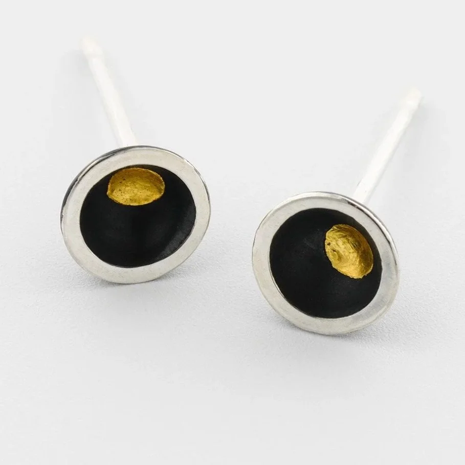 Close-up of domed oxidised silver stud earrings showing central gold keum boo dot and polished edge detail