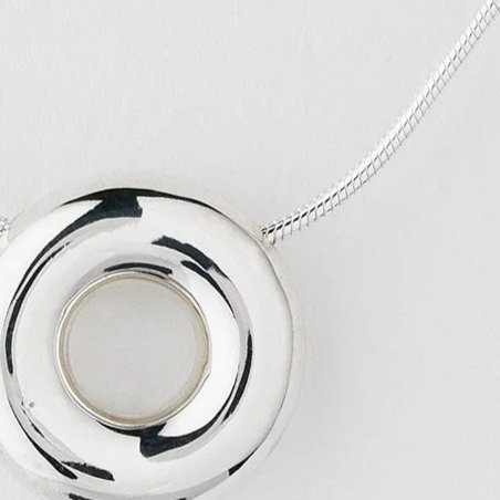 Close-up of Monad small necklace showing polished torus pendant in sterling silver