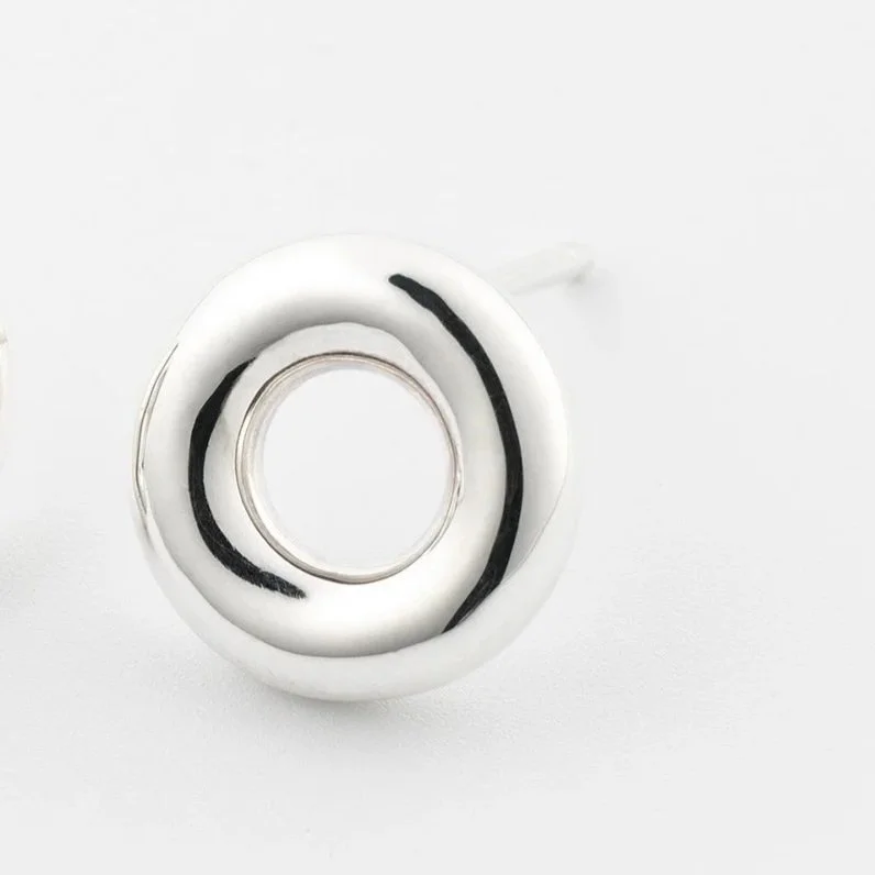 Close-up of Monad mini stud earrings, polished circular torus form in sterling silver