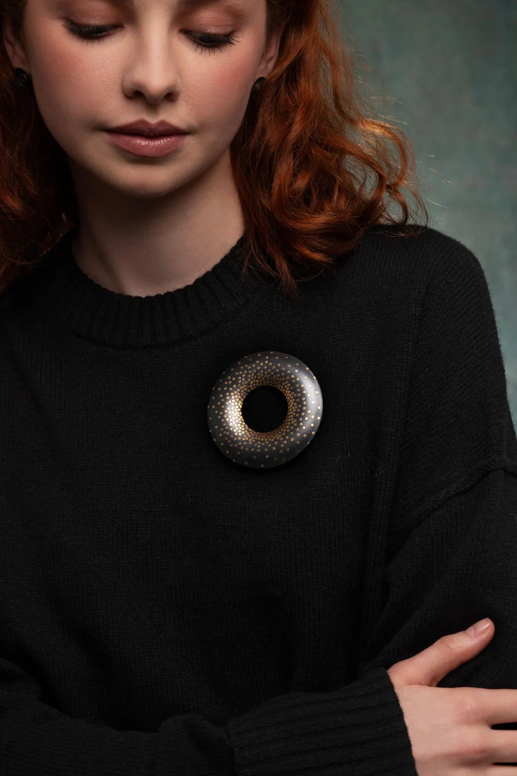 Model wearing oxidised sterling silver Oblivion brooch with scattered 24ct gold keum boo dots on black knit jumper.