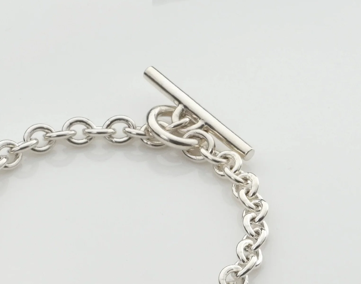 Close-up of Monad chain bracelet showing hollow torus link and T-bar clasp in sterling silver