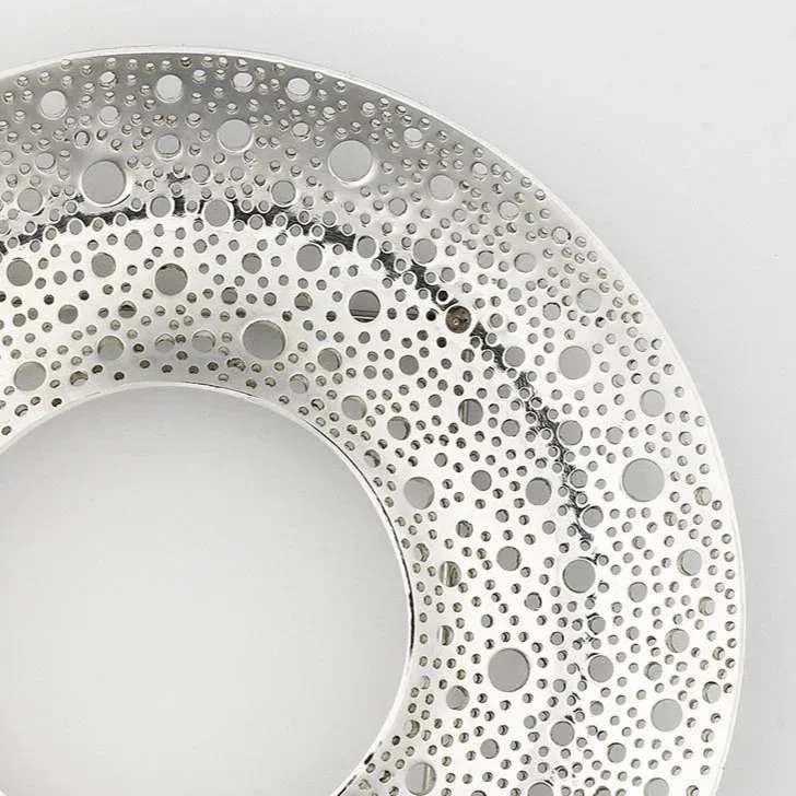 close up of Sum Brooch in sterling silver with hand-pierced lace-like circular surface and polished finish
