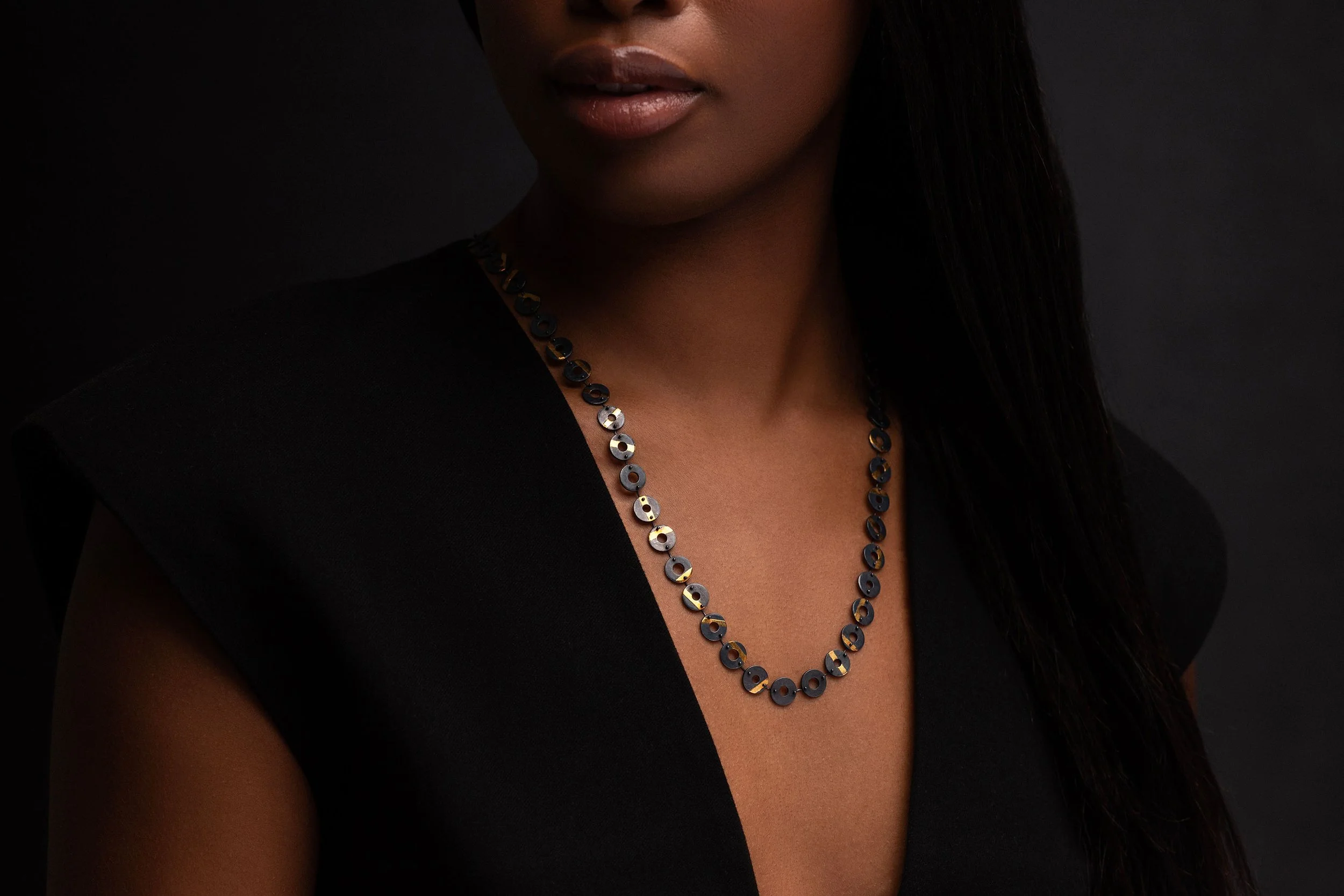 Model wearing Chronos necklace, oxidised torus links with gold stripes