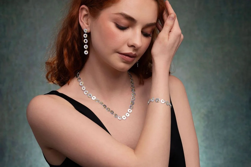 Model wearing Kairoi statement earrings, linked torus circular shapes in sterling silver with gold detail