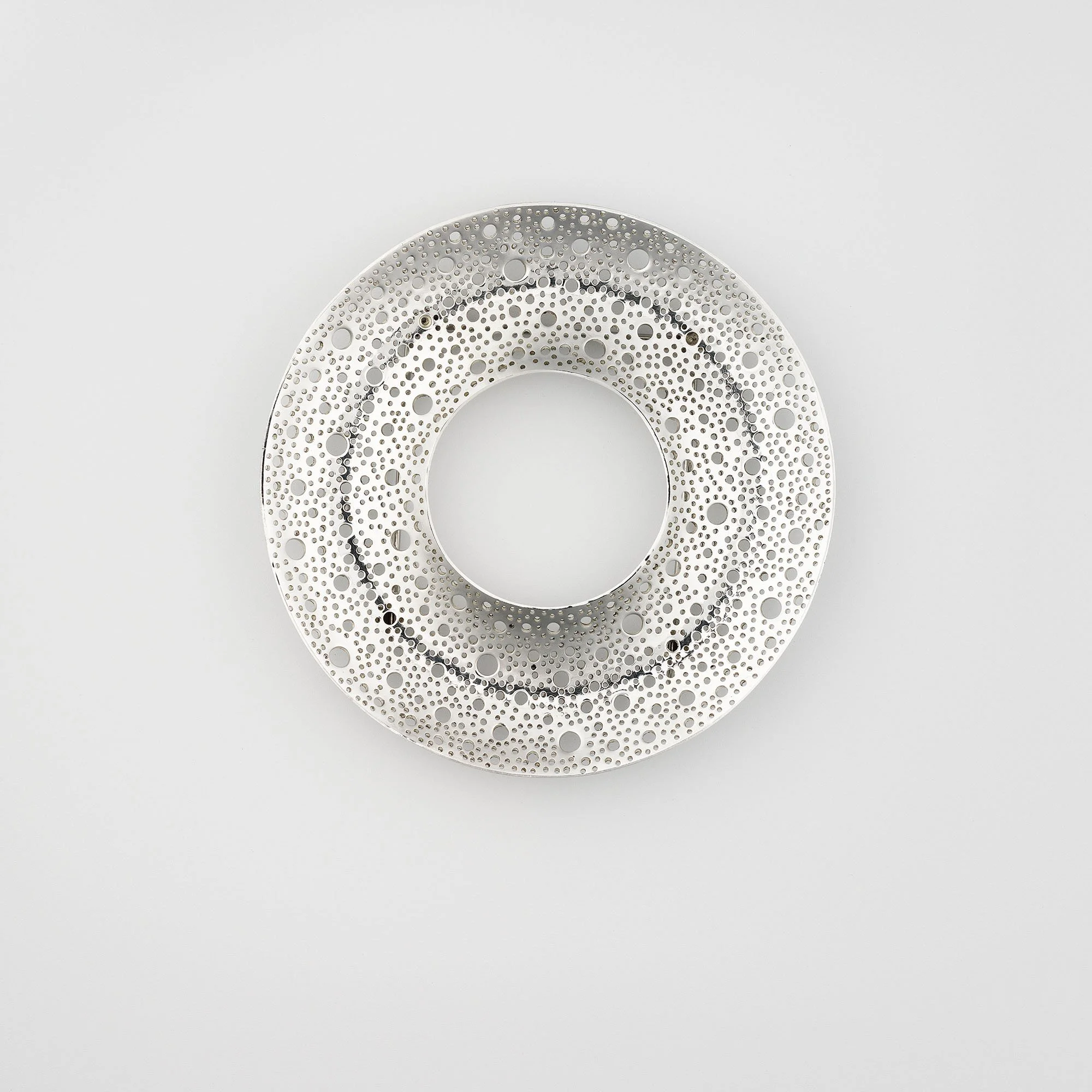 Sum Brooch in sterling silver with hand-pierced lace-like circular surface and polished finish