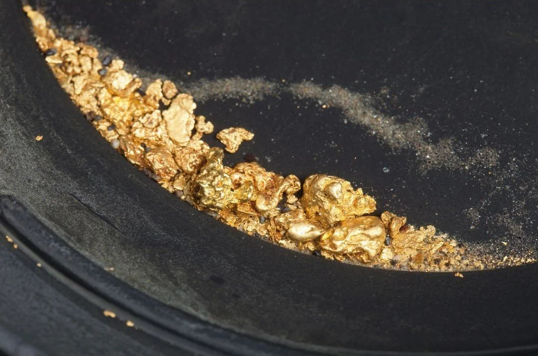 Fairtrade gold grain and nuggets in a dark pan, used in ethical jewellery making.