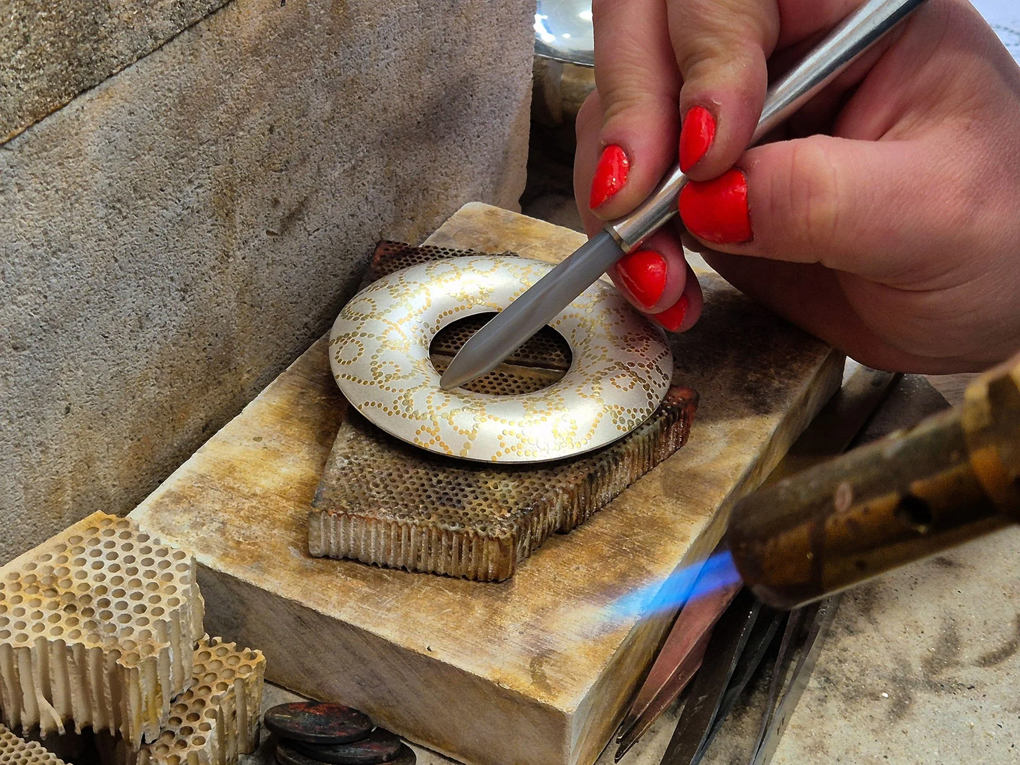 Applying keum boo to the Interlace brooch, heating the silver and burnishing gold onto the surface