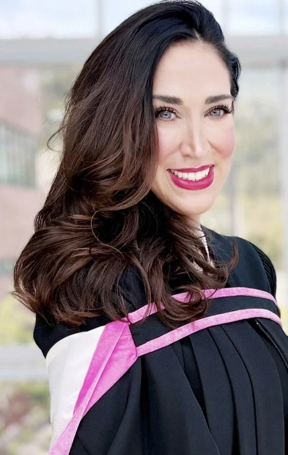 Woman in graduation gown smiling outdoors