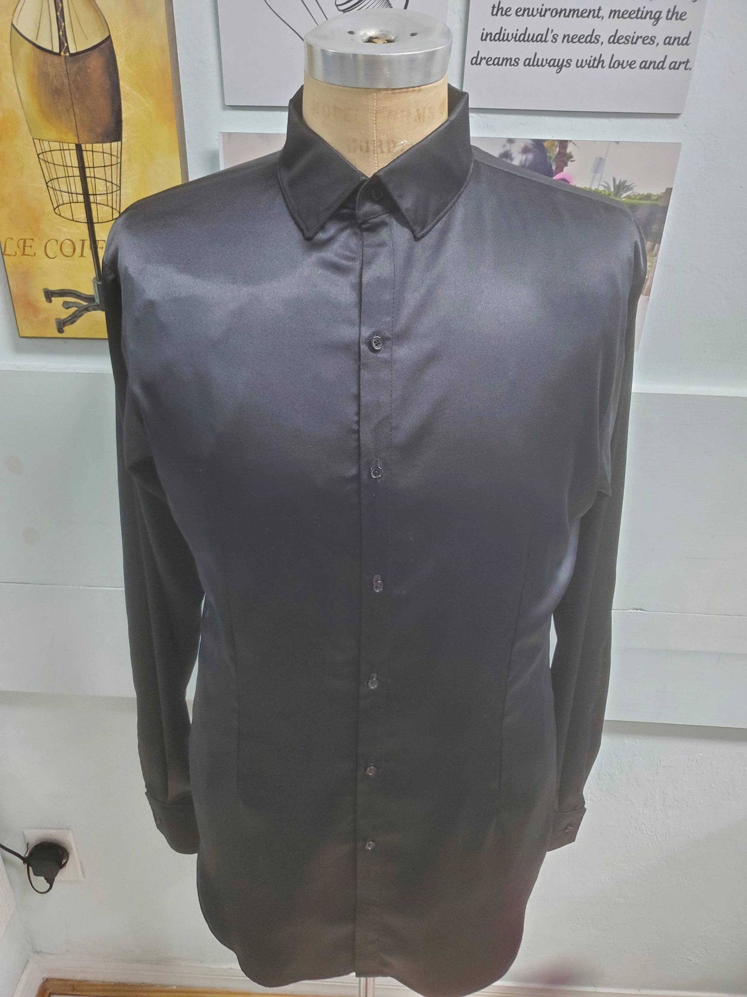 Black satin button-up shirt on a mannequin torso in a store or display area.