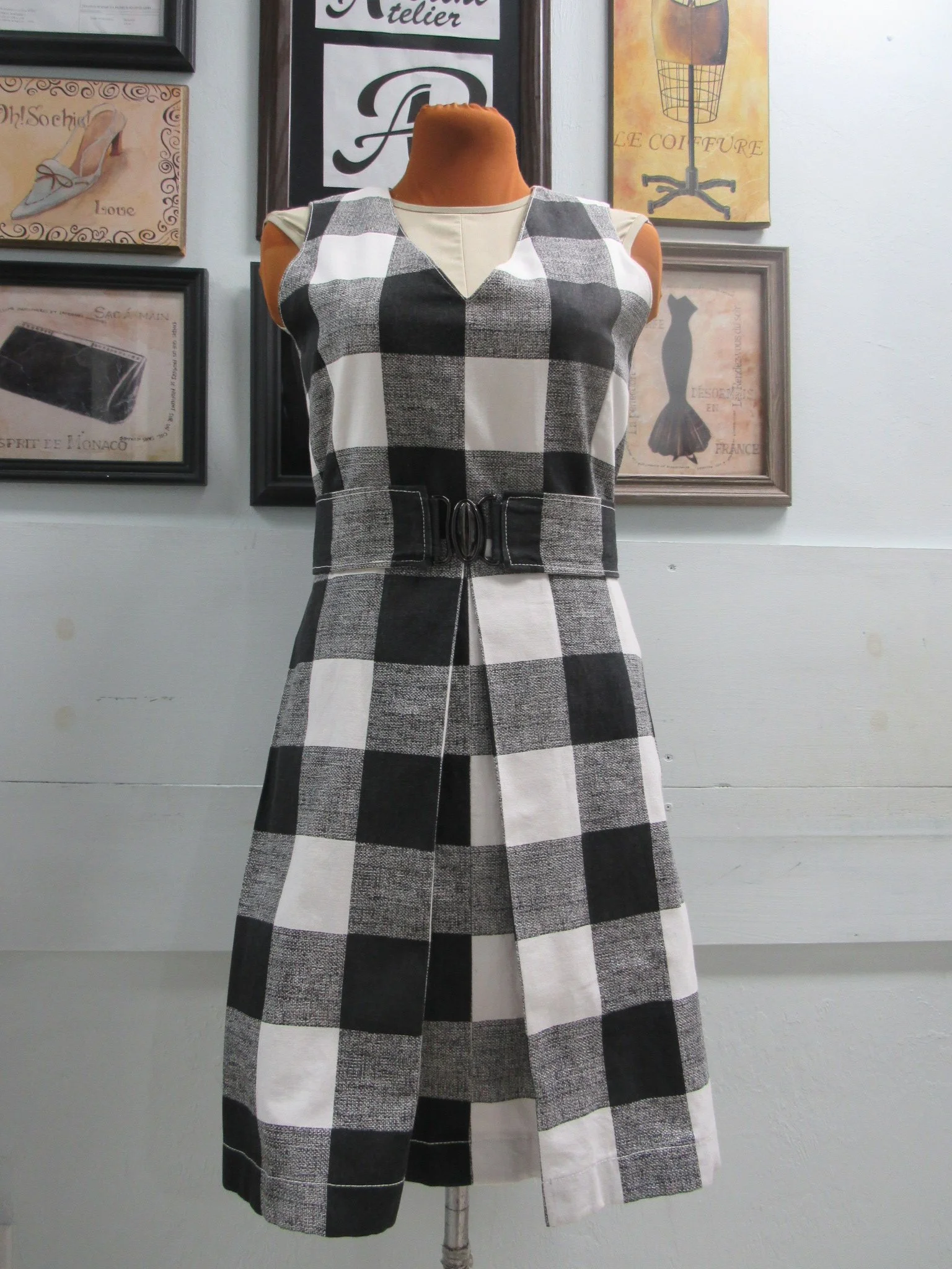 Black and white checkered sleeveless dress with a belt displayed on a mannequin.