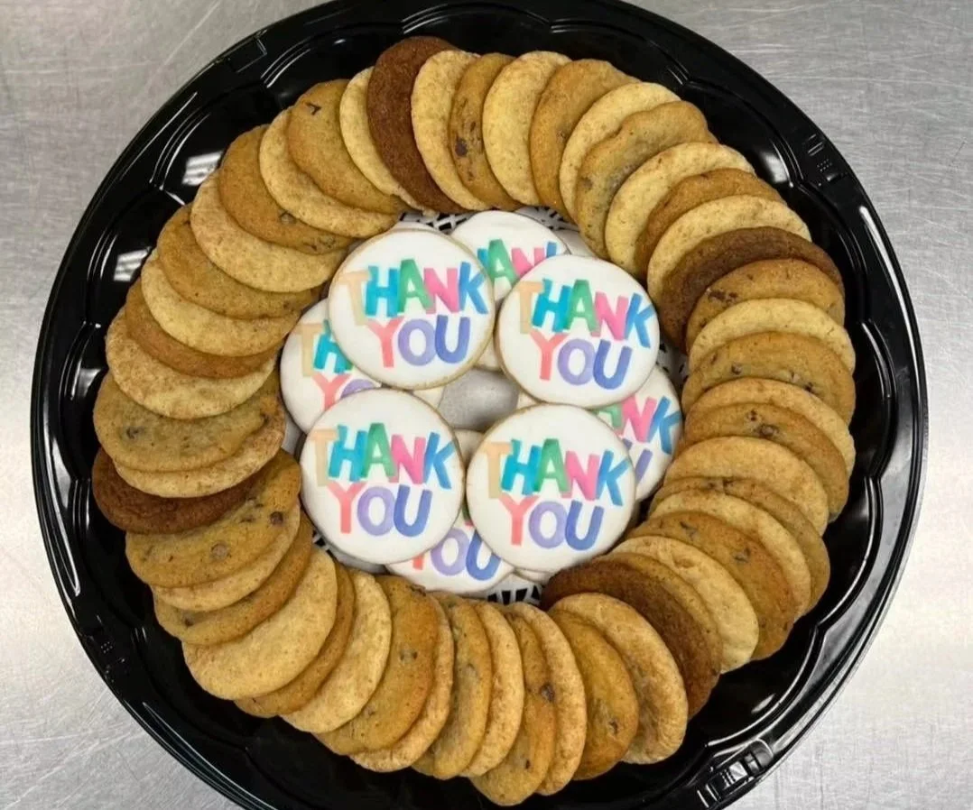 A circular arrangement of chocolate chip cookies surrounding five cookies decorated with 'Thank You' in colorful letters.