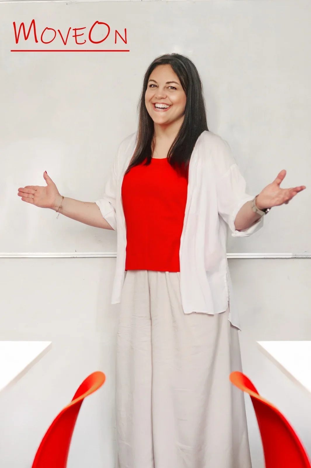 A smiling woman with long dark hair standing in front of a whiteboard with the word 'MoveOn' written in red. She is wearing a red top and beige pants, with her arms outstretched.