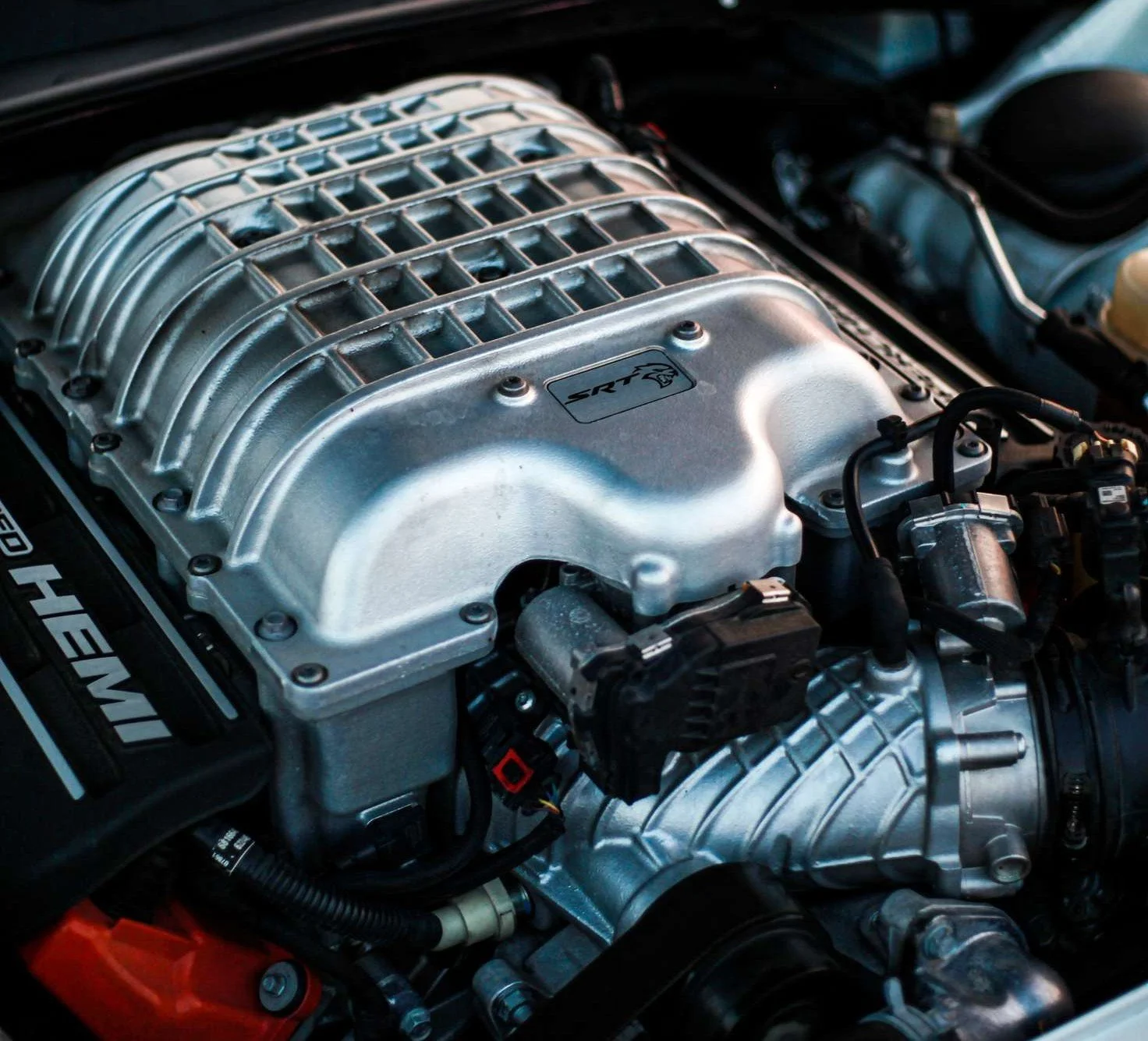 Close-up of a supercharged engine with the label 'SRT' on the silver intake manifold.