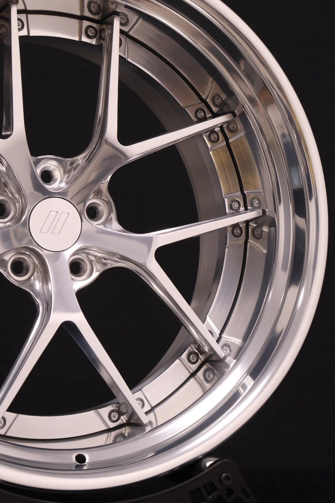 Close-up of a shiny, silver alloy wheel with a multi-spoke design against a black background.