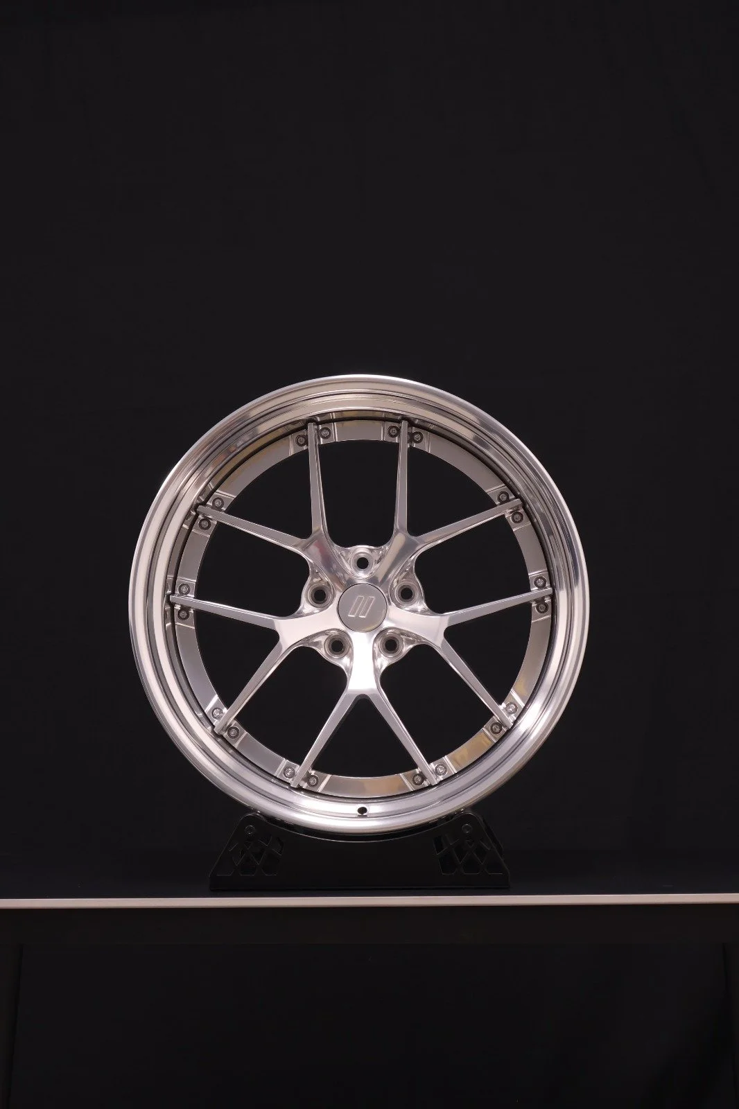 A silver-colored, multi-spoke car wheel rim displayed against a black background.