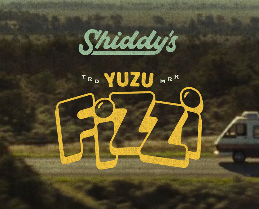 Text overlay on a blurred outdoor scene with a camper trailer and trees, reading 'Shiddy's Yuzu' with stylized English and Japanese characters.