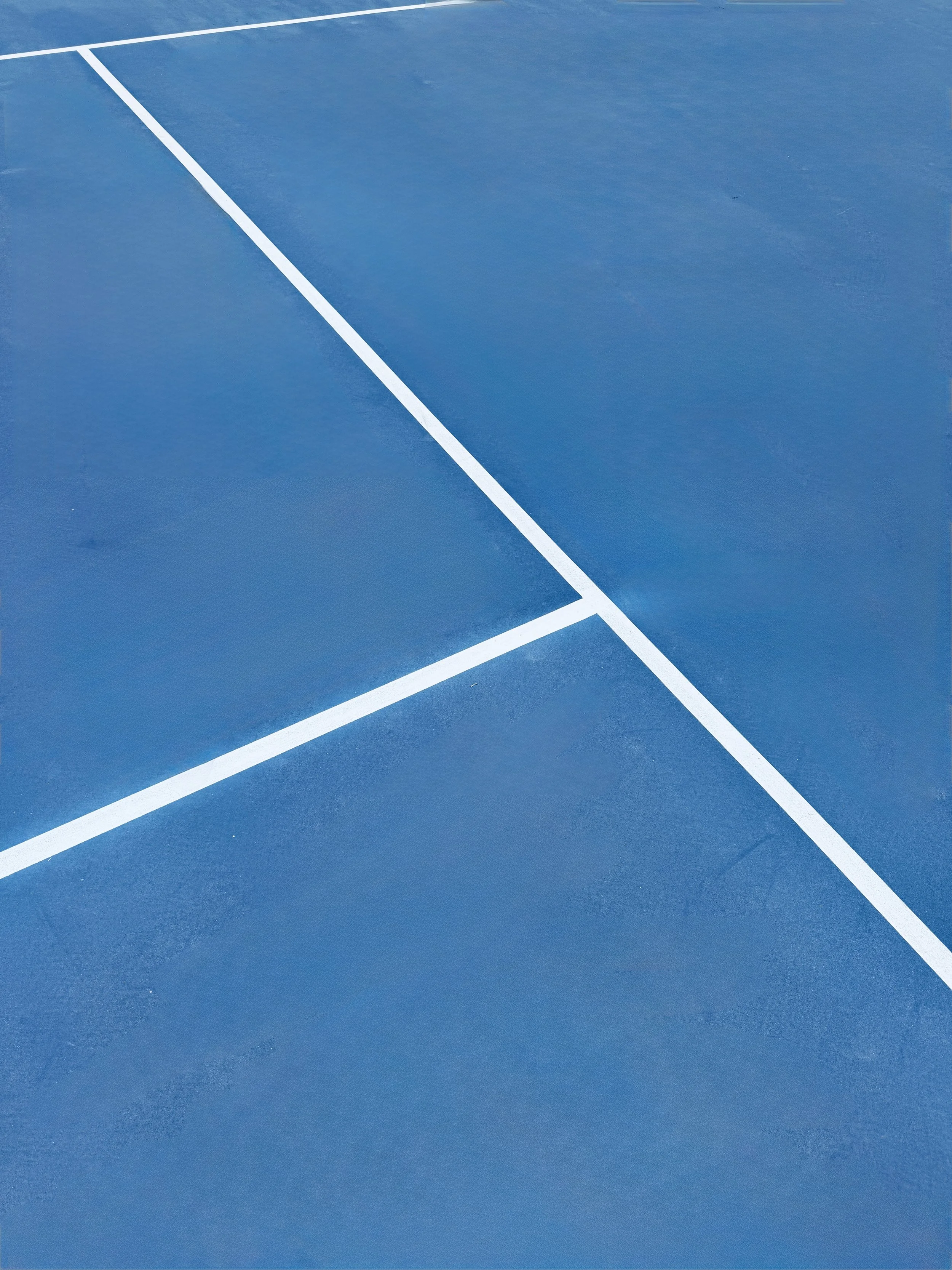 Close-up of a blue tennis court with white boundary lines.