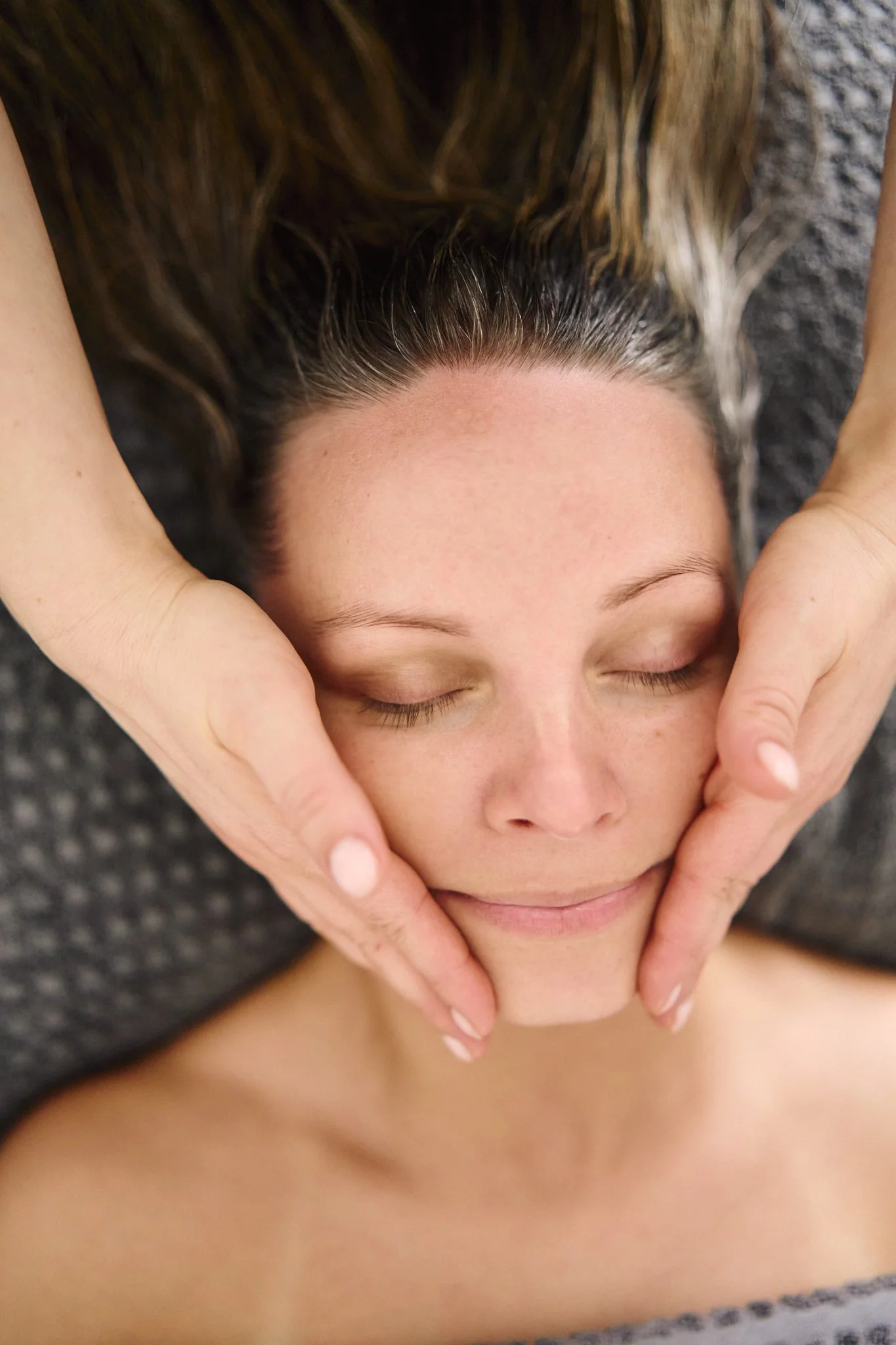 Massage therapist Gabriella Bloom providing a relaxing facial massage in her serene home spa setup in Fleet, Hampshire.