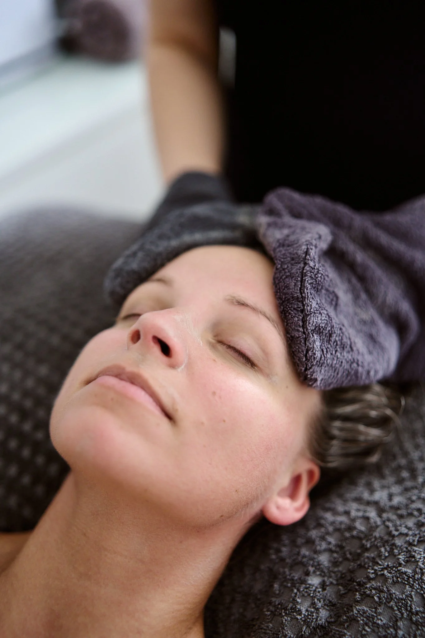 Massage therapist Gabriella Bloom providing a relaxing facial massage in her serene home spa setup in Fleet, Hampshire.