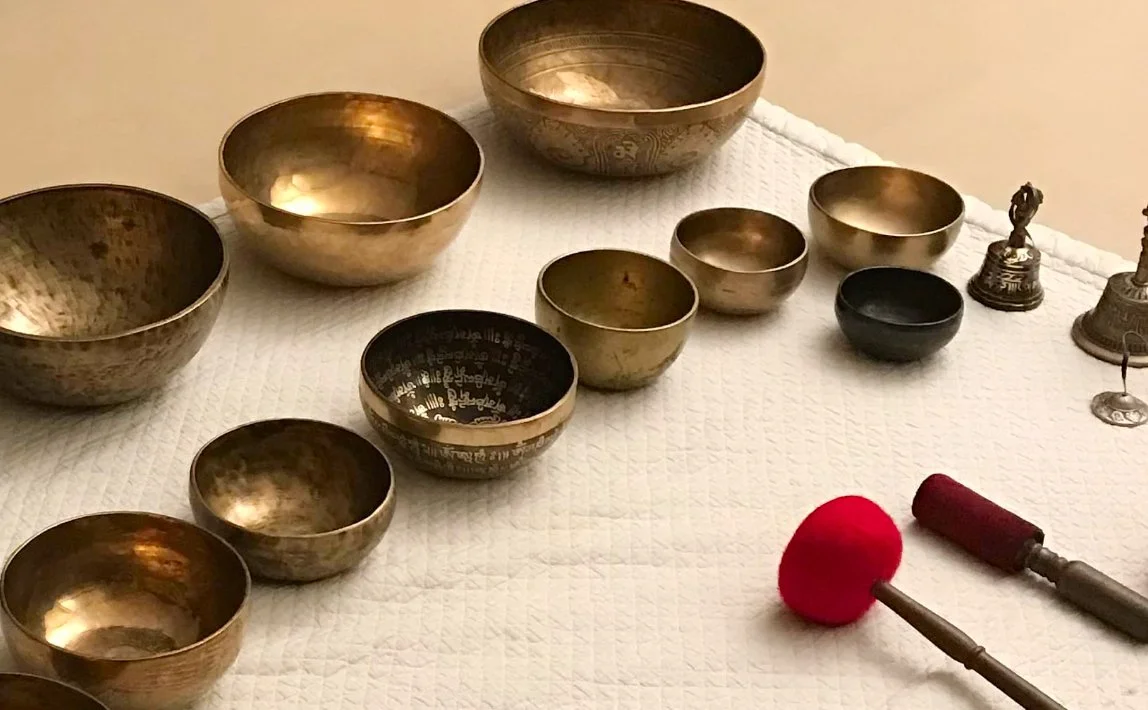 Verschiedene tibetische Klangschalen und Ritualgegenstände auf einem weißen Tisch.